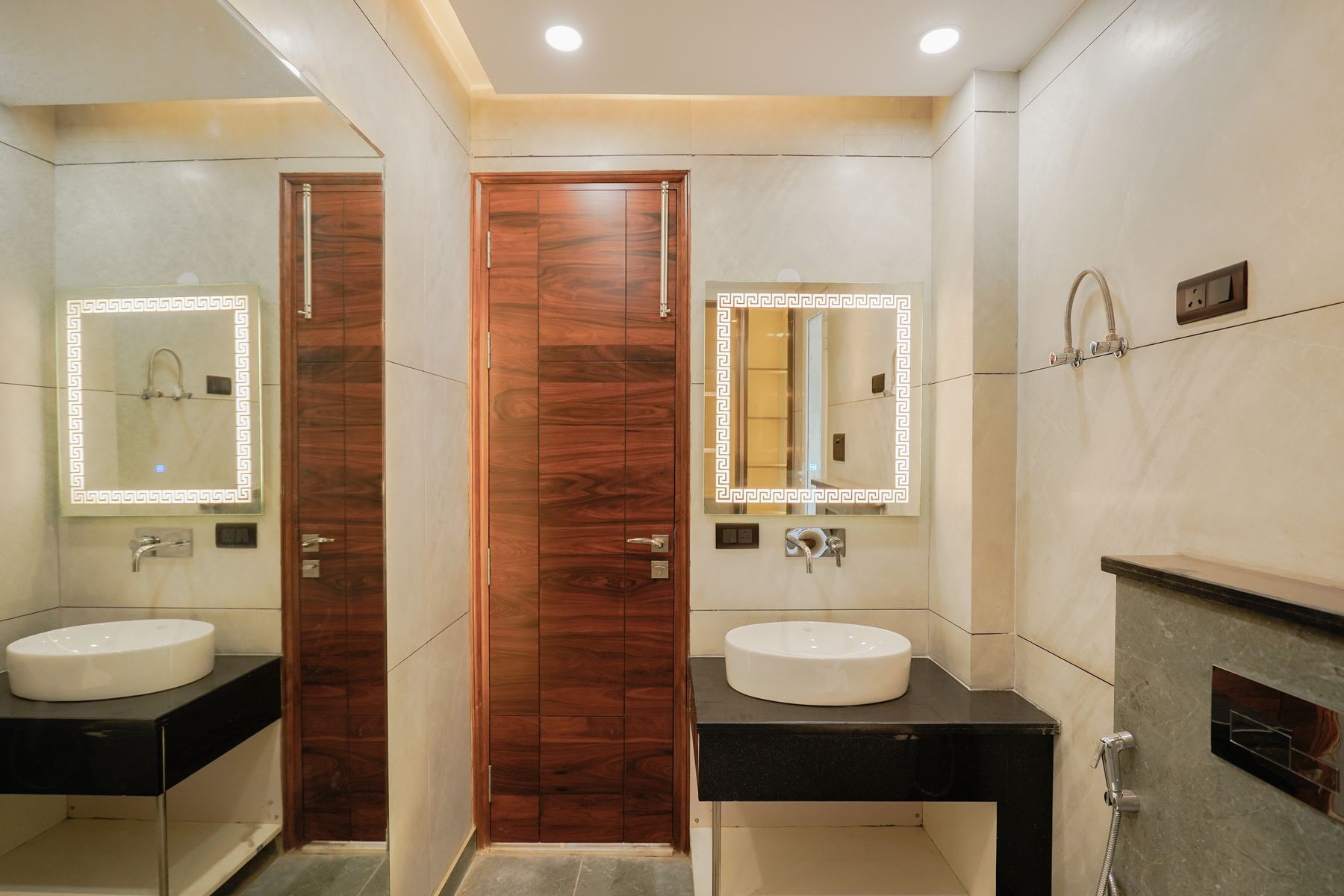 Bathroom with backlit mirrors, vessel basins and veneer door