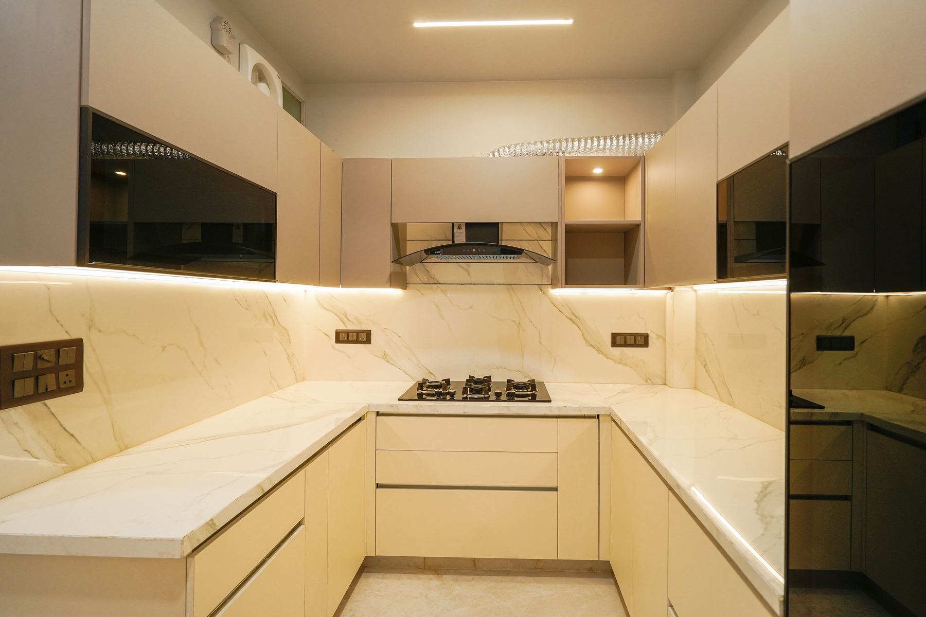 U-shaped modular kitchen with marble backsplash and under-cabinet lighting